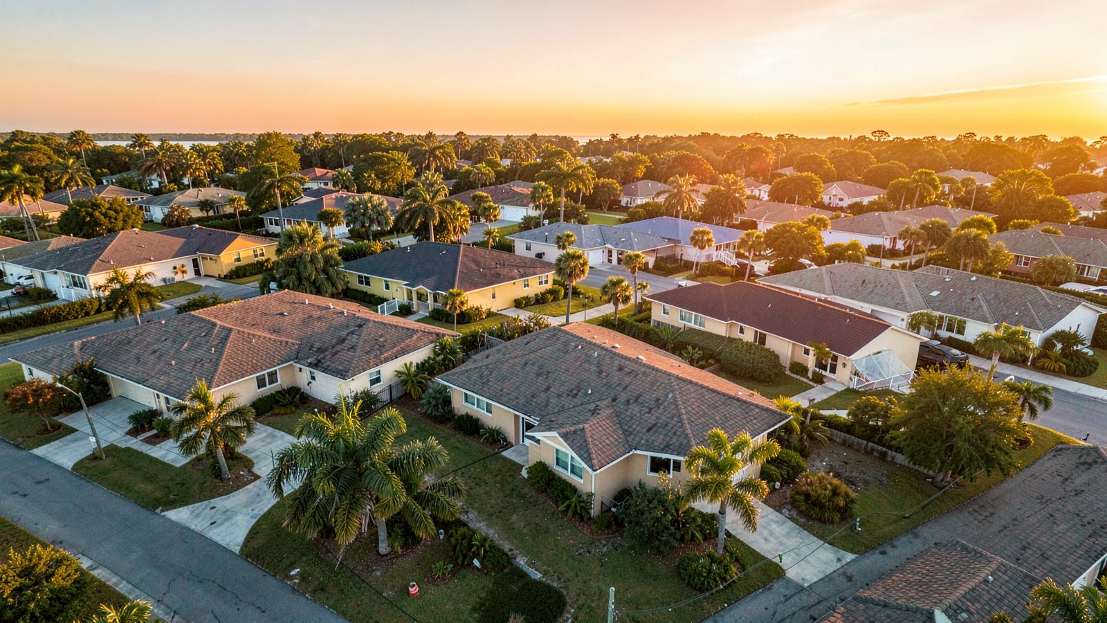Aerial view of a Florida neighborhood with new shingle and tile roofs at golden hour